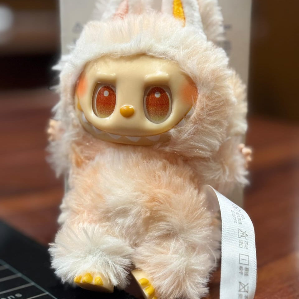 Plush toy with large eyes and yellow accents on a wooden surface